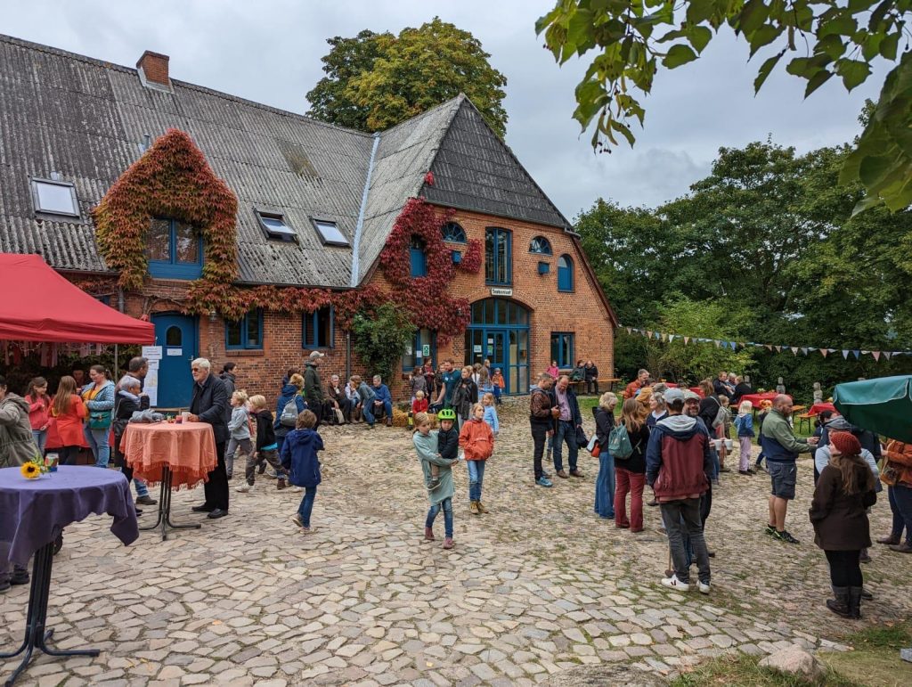 Menschen sind vor dem Backsteingebäude des Haupthauses versammelt