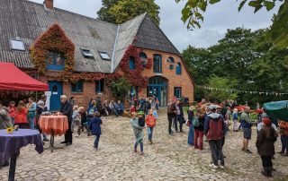 Menschen sind vor dem Backsteingebäude des Haupthauses versammelt