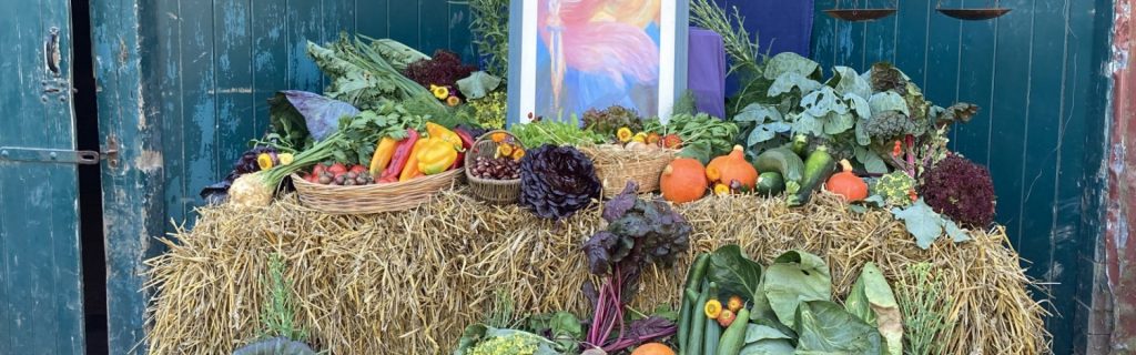 ein Altar-Tisch mit Gemüse, Obst und Bild im Hintergrund