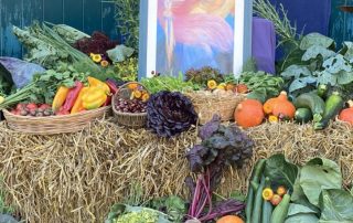 ein Altar-Tisch mit Gemüse, Obst und Bild im Hintergrund