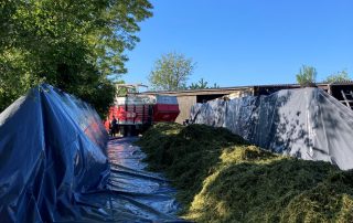 ein LKW ist mitten in einem Hof geparkt neben einem großen Heuhaufen