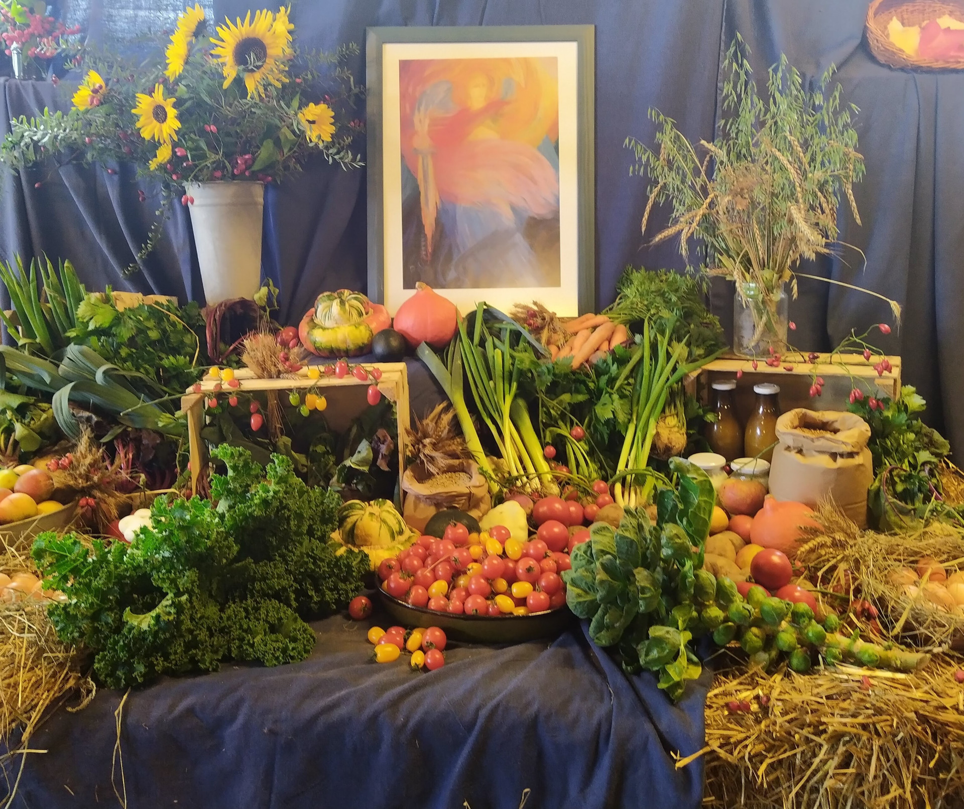 ein Altar-Tisch mit Gemüse, Obst und Bild im Hintergrund